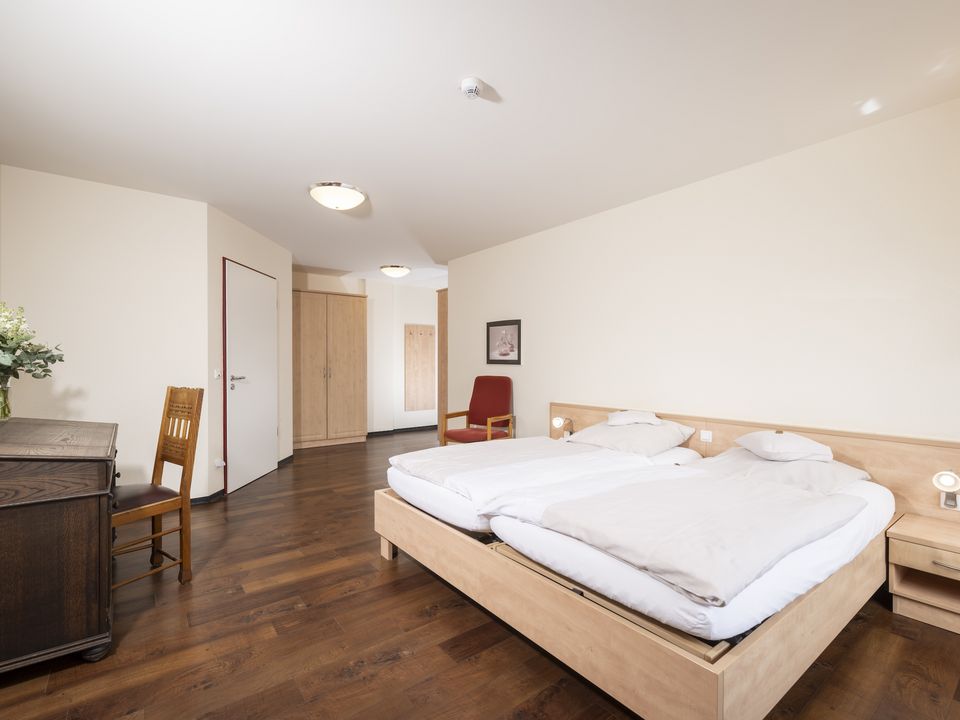 Blick ins Doppelzimmer: Doppelbett, Schreibtisch und Eingangstür