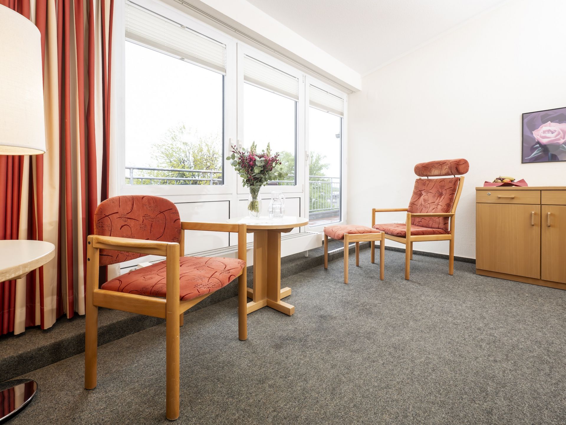 Blick ins Einzelzimmer: Sitzgelegenheit, Anrichte und kleiner Tisch