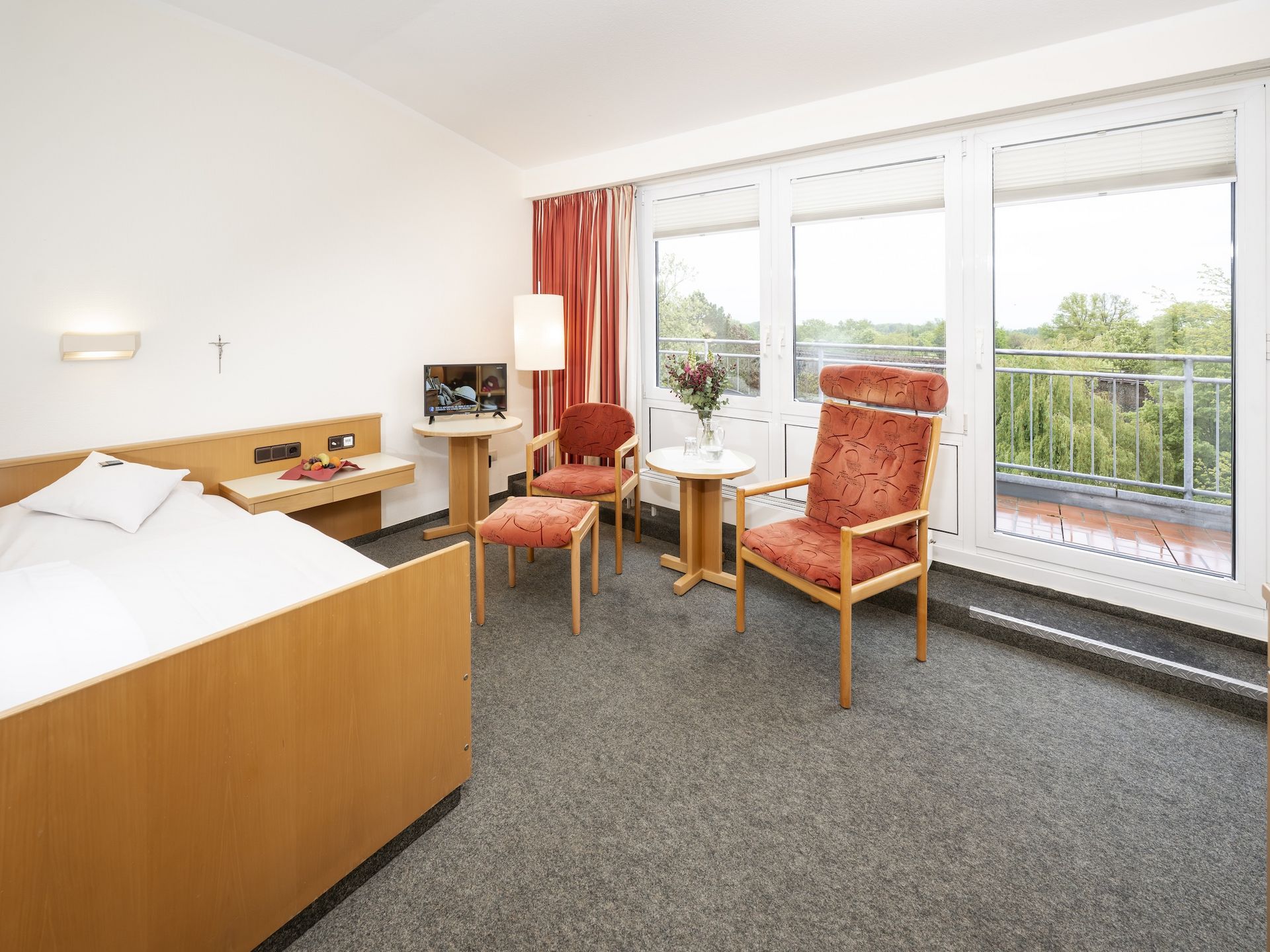 Blick ins Einzelzimmer: Bett, Sitzecke und Fernseher am Fenster