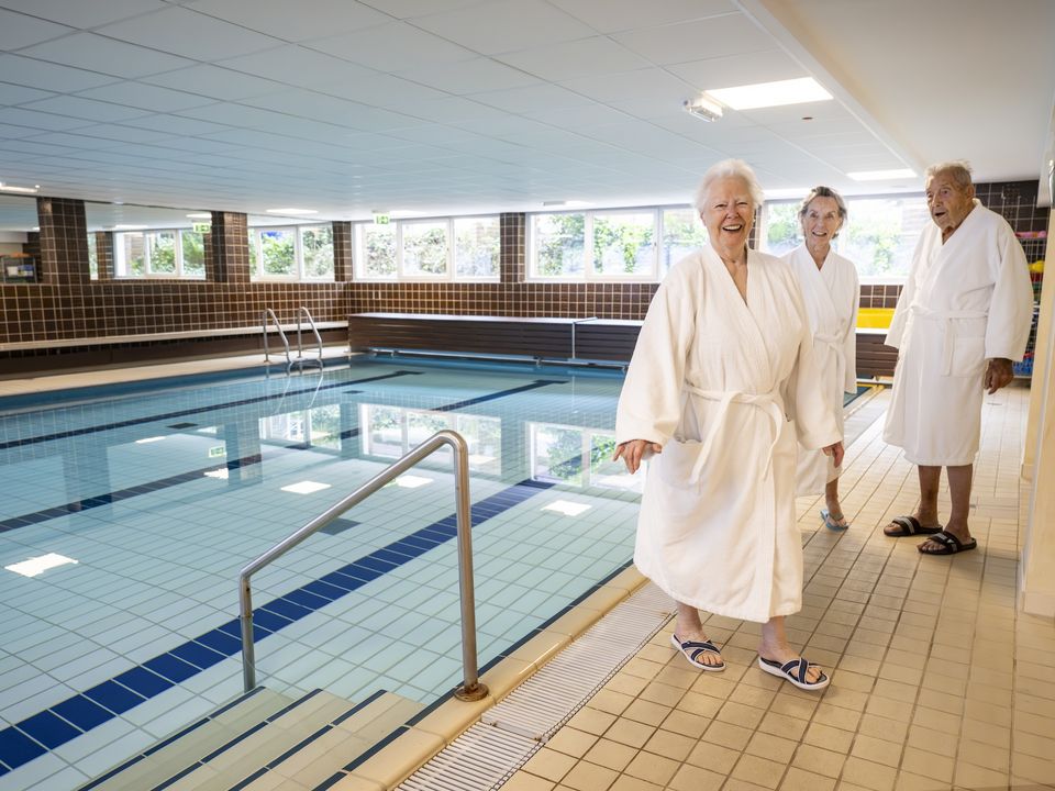 Drei Personen in weißen Bademänteln im Schwimmbad