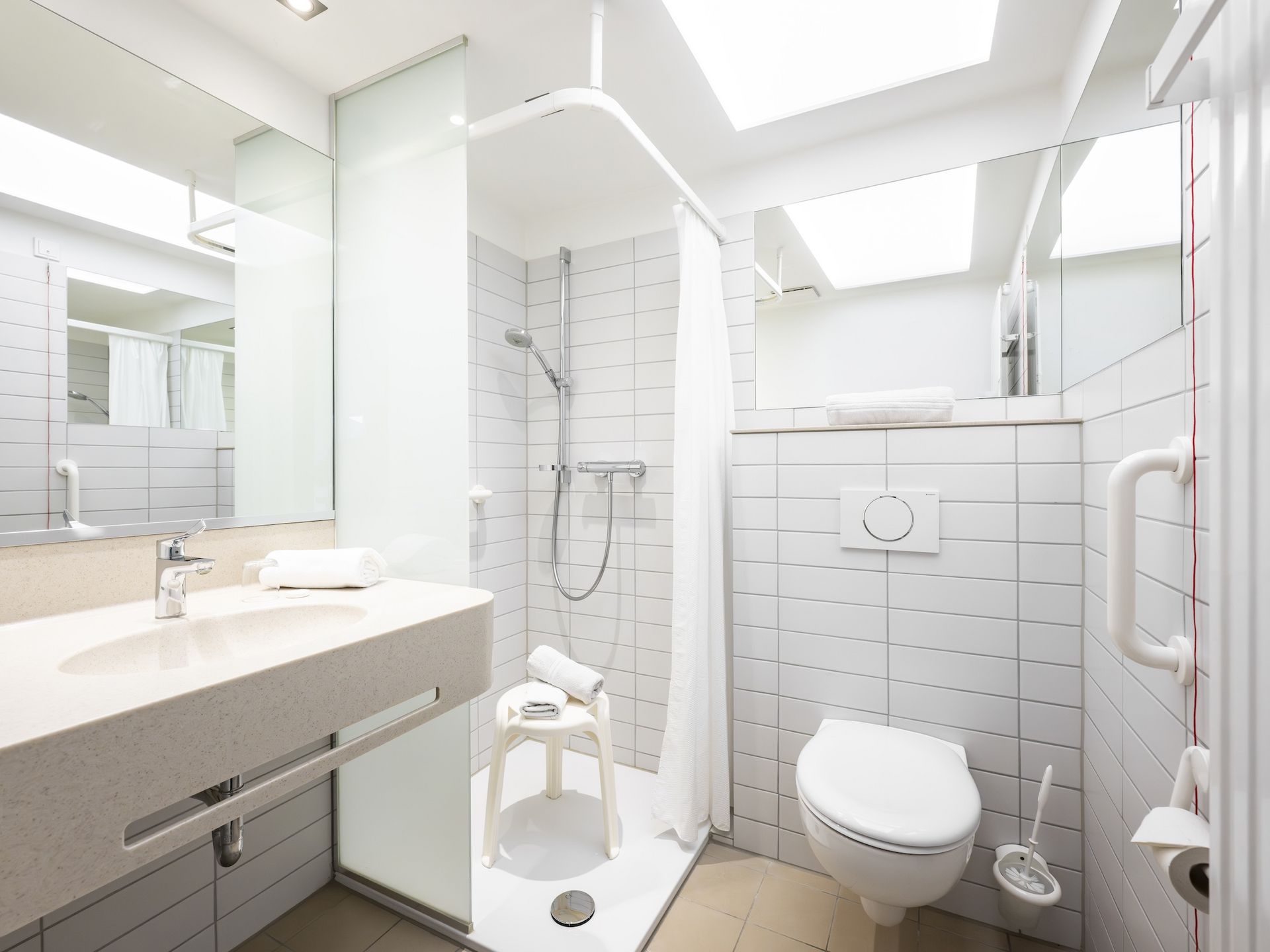 Blick ins Bad: WC, Dusche und Waschbecken, mit Aufstehhilfen