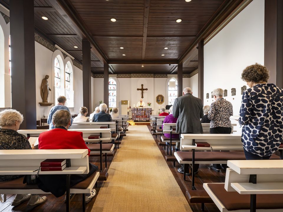 Mehrere Personen sitzen auf Bänken in der Kapelle. Gleich beginnt ein Gottesdienst