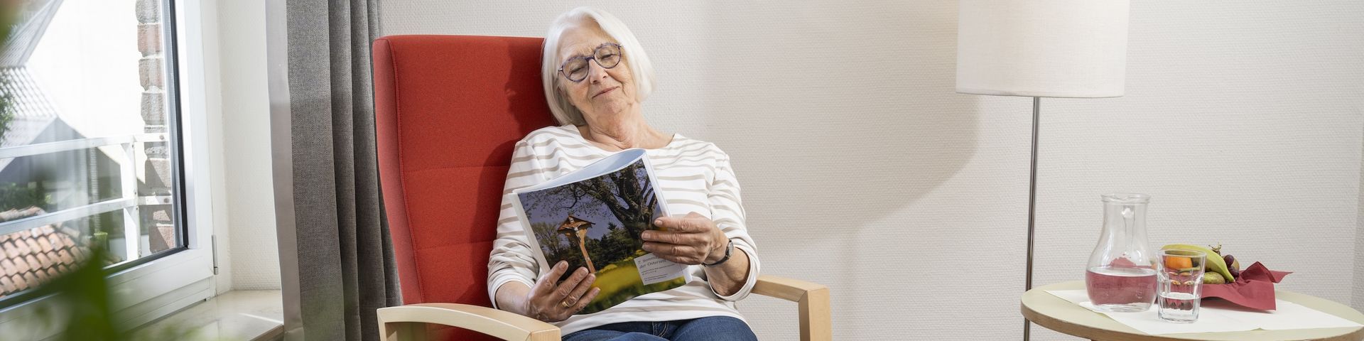 Eine Frau liest auf ihrem Zimmer im Sessel