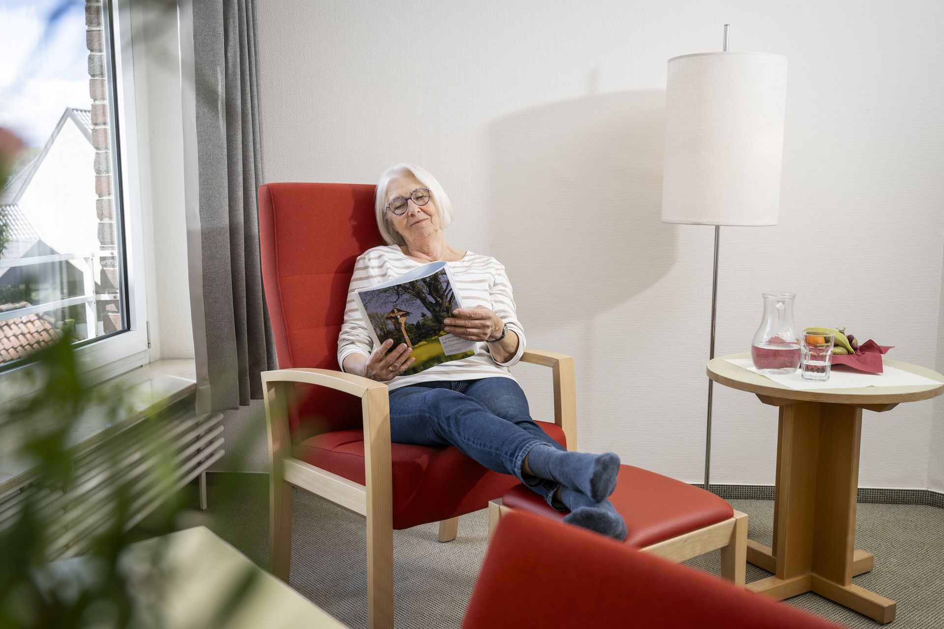 Eine Frau liest auf ihrem Zimmer im Sessel