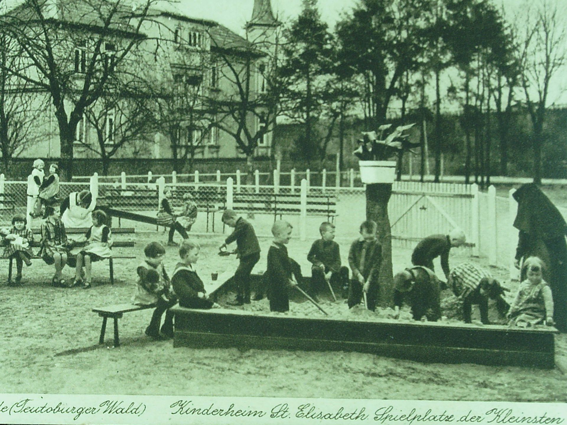 Ein altes Schawrz-Weiß-Bild: Kinder und Schwestern im Sandkasten
